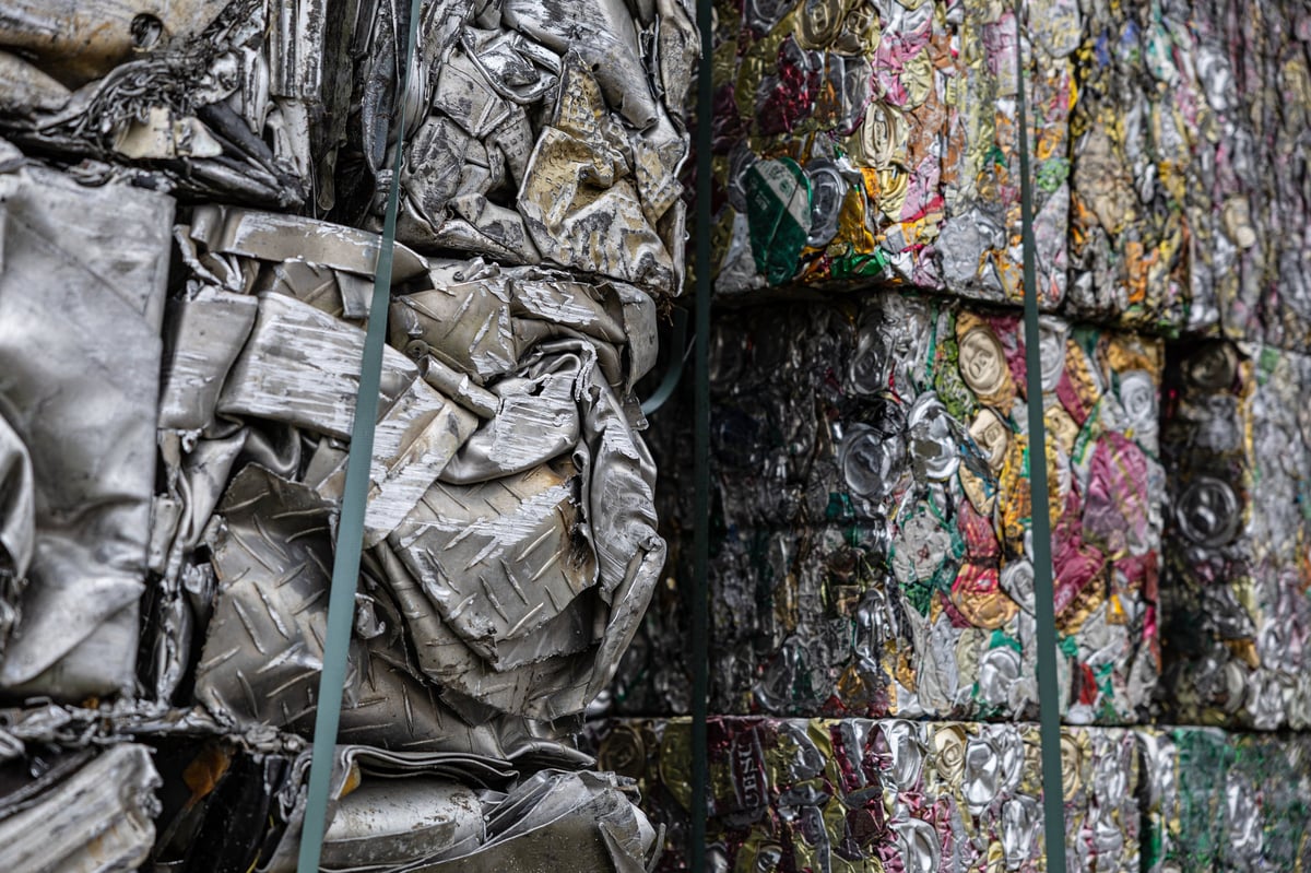 Industrial piles of compressed scrap metal and colorful aluminum cans bundled in blocks, ready for recycling and reuse