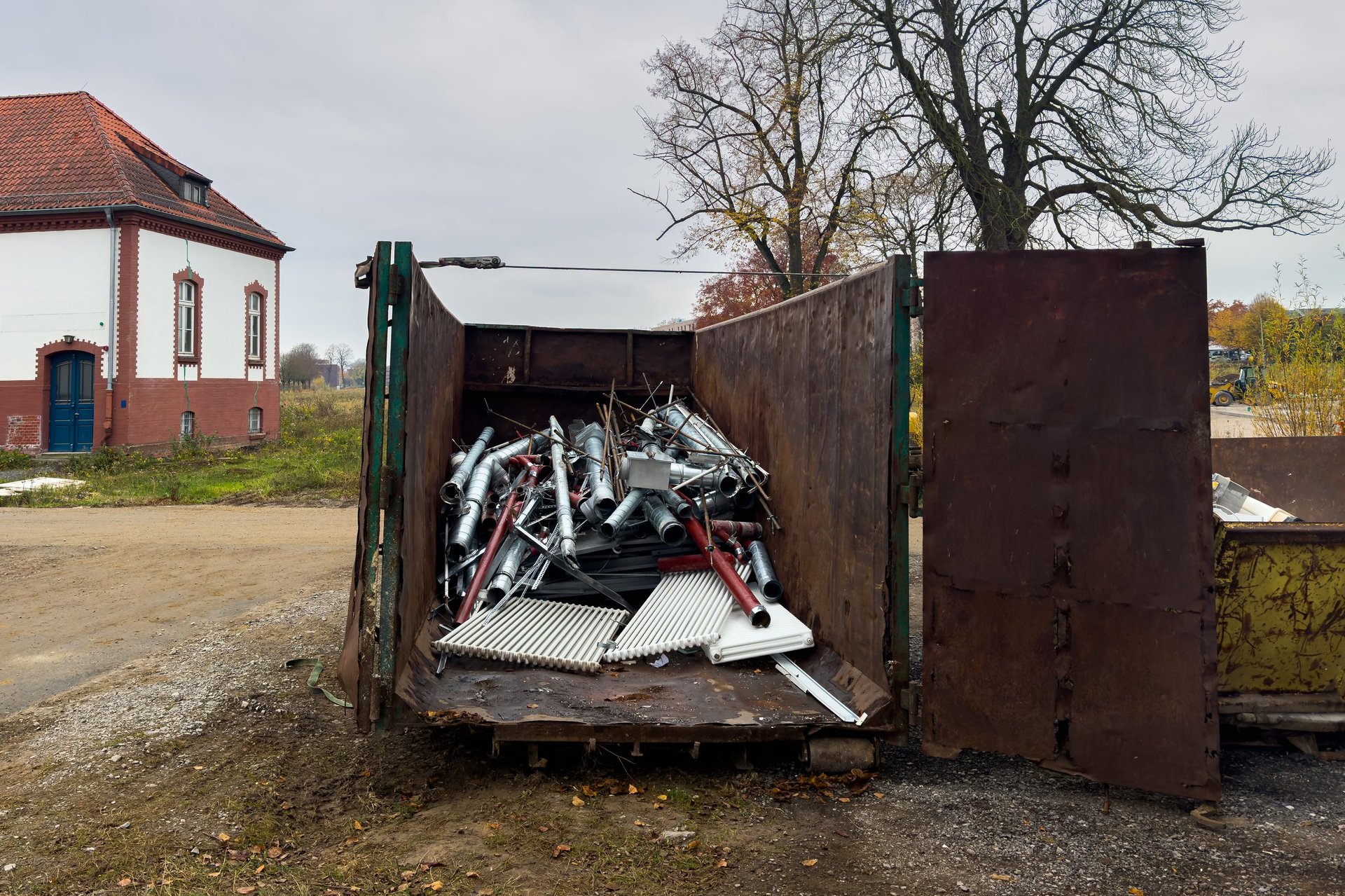 A large dumpster filled with scrap metal sits in an open area.